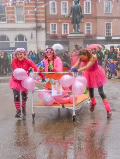 Competitors pushing a decorated pink bed through Romsey town centre