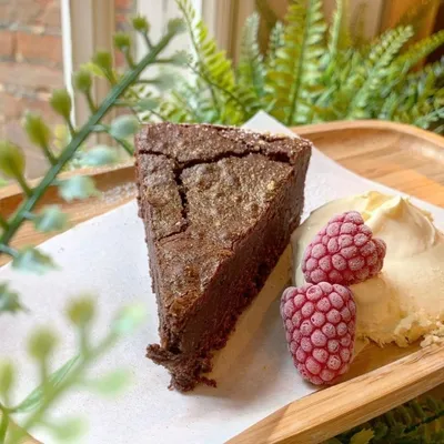 A slice of chocolate cake with a fewsh raspberry